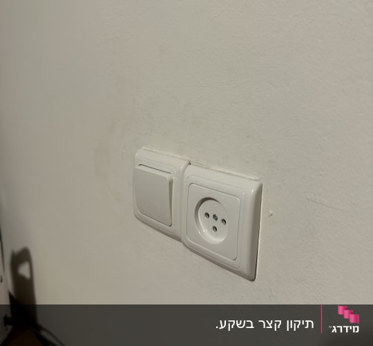 שקע חשמל ומתג על קיר לבן
